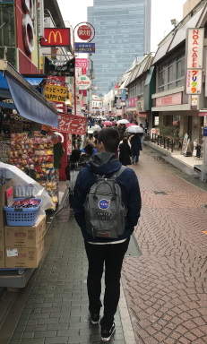 a man wearing a backpack walks down a city street