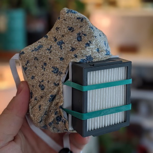 a close up of a face mask made of flower-patterned cloth with a grey and white filter on the front